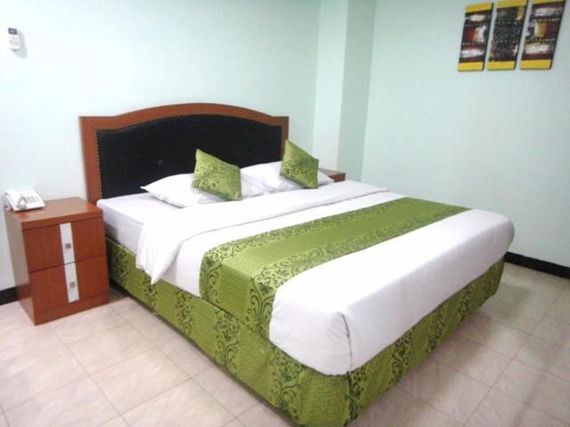 雅加达卡萨屋特玛酒店的一间卧室配有一张带绿色和白色床单的大床