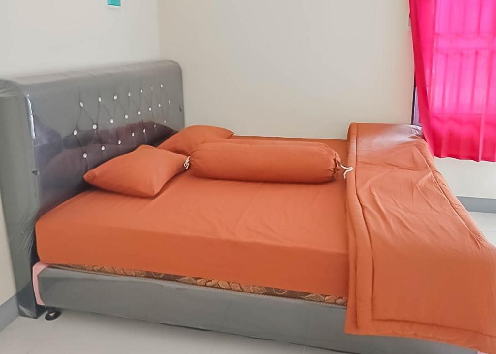 山口洋Homestay Verisha Mitra RedDoorz的一张带橙色床单和枕头的床