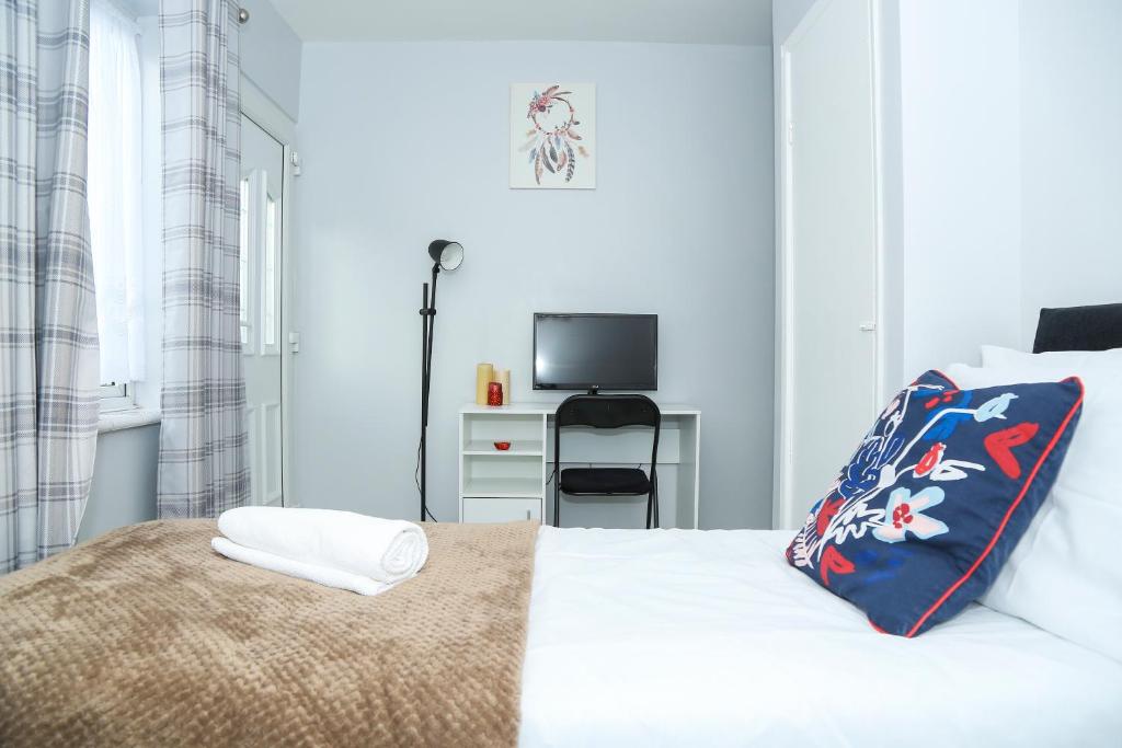 KentWilmington Lodge Dartford London的一间白色卧室,配有床和电视