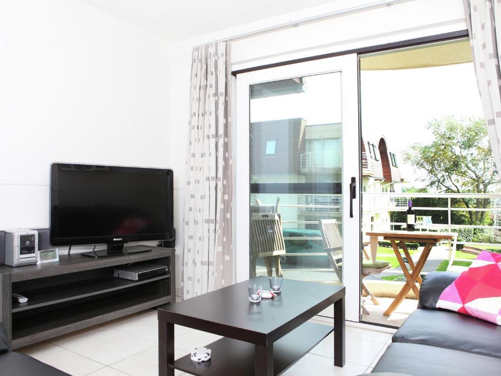 布列登Stylish Apartment in Bredene with Pool的客厅配有平面电视和桌子。