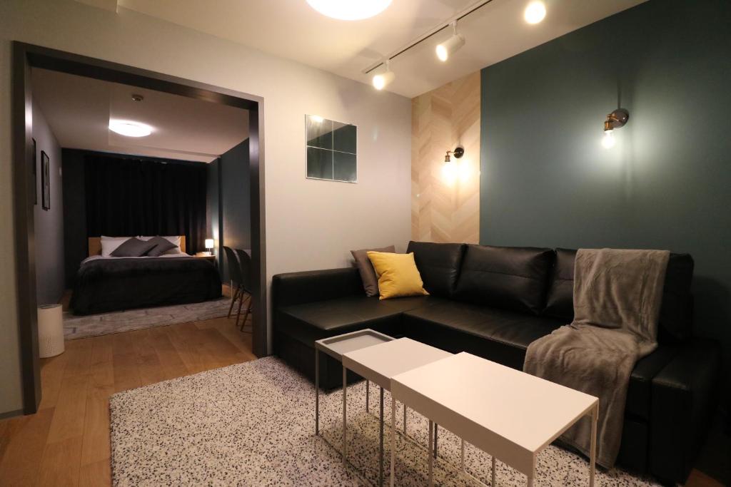 札幌Glass Shiseikan的客厅配有黑色沙发和床。