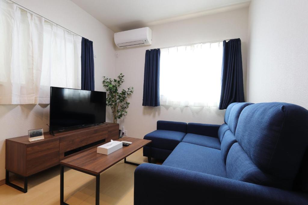 大阪5 minutes Shin-Osaka 3的客厅配有蓝色的沙发和电视