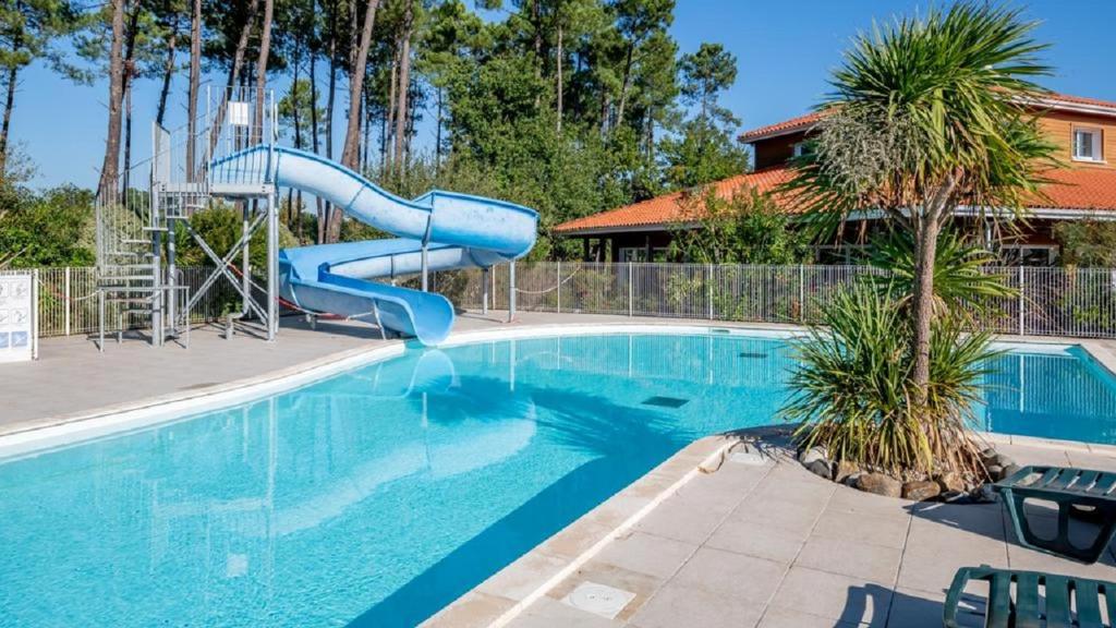 波讷地区帕朗提Laouchet Le Hameau des Grands Lacs的一座房子里一个带蓝色滑梯的游泳池