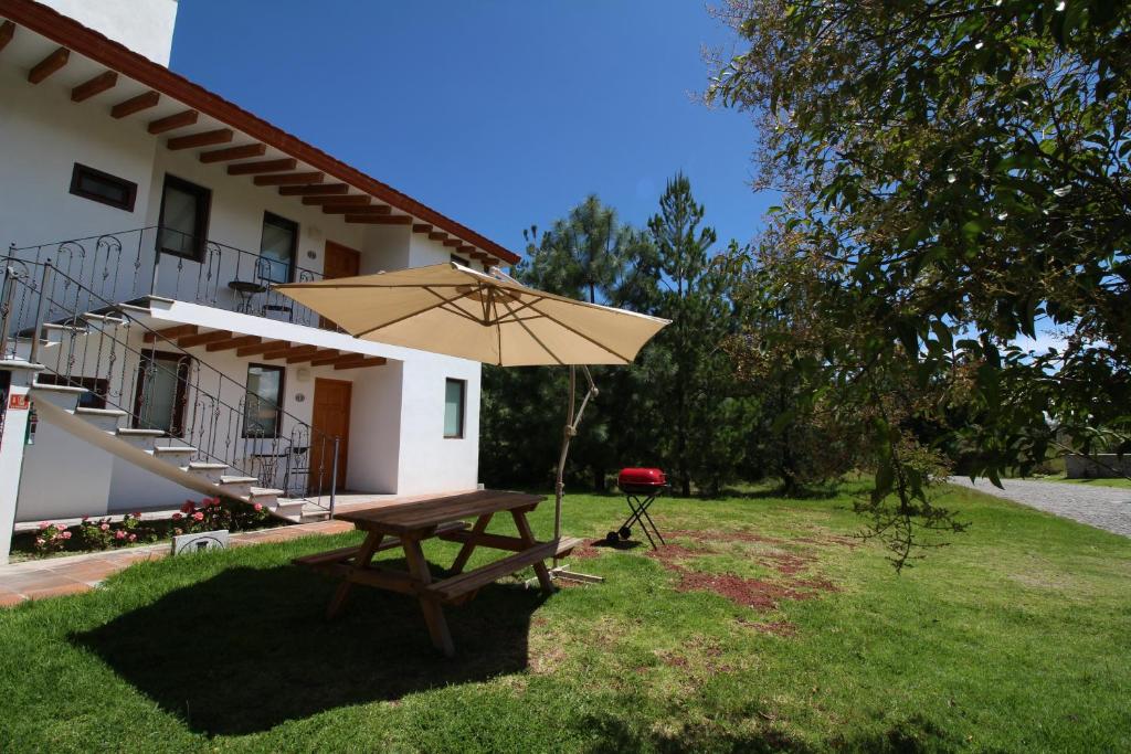 瓦曼特拉Hacienda Soltepec Suites Campo de Golf的房屋前带雨伞的野餐桌