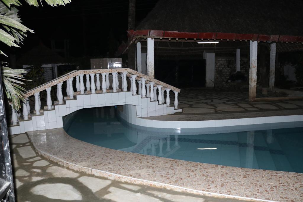 蒙巴萨Room in Guest room - A wonderful Beach property in Diani Beach Kenya的夜间在游泳池上方的木桥