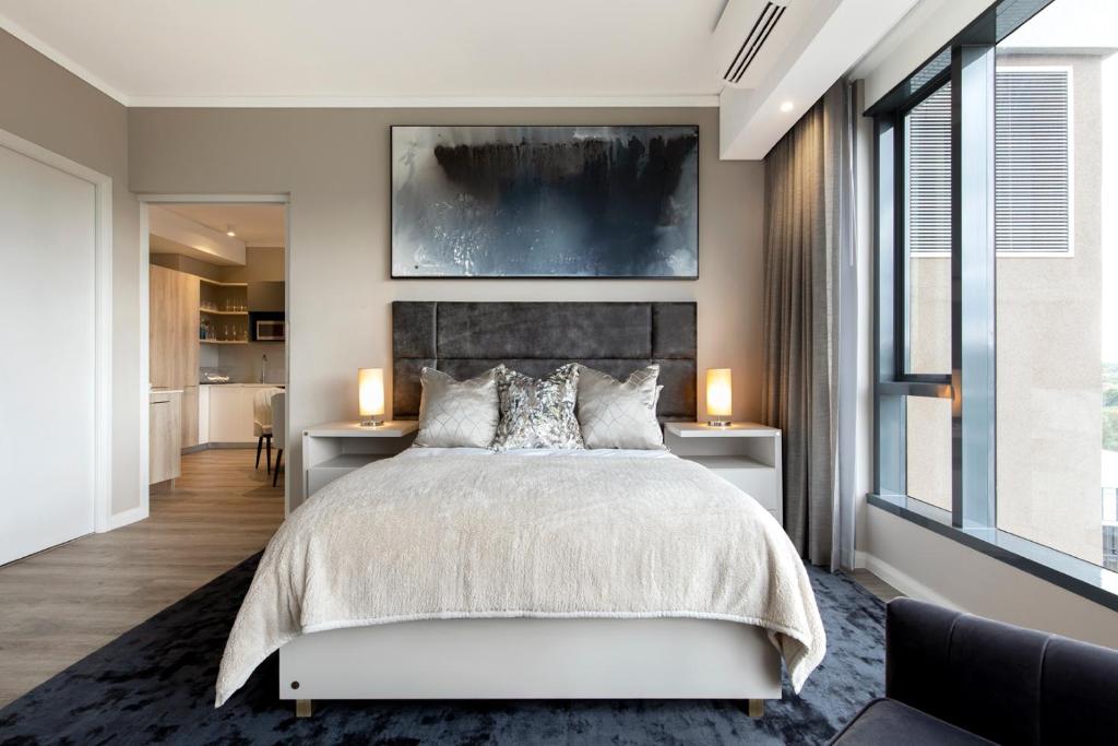 比勒陀利亚Black Marble - Menlyn Residence Apartments的一间卧室配有一张大床和两张带台灯的桌子。