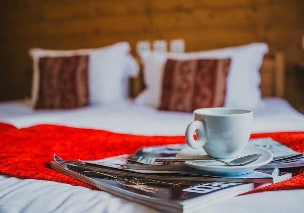 美贝尔Hôtel Les Grangettes的床上的桌子,上面有咖啡杯和盘子
