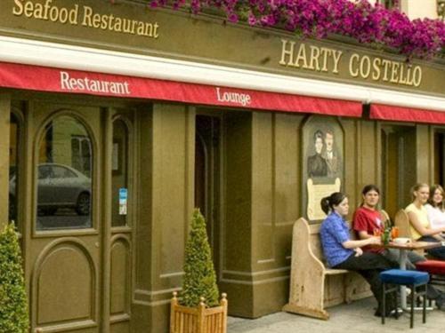 巴利巴宁Harty Costello Town House的一群人坐在餐厅外的桌子上