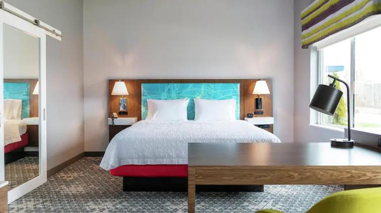 基西米Hampton Inn Kissimmee North的配有一张床、一张书桌和一扇窗户的酒店客房