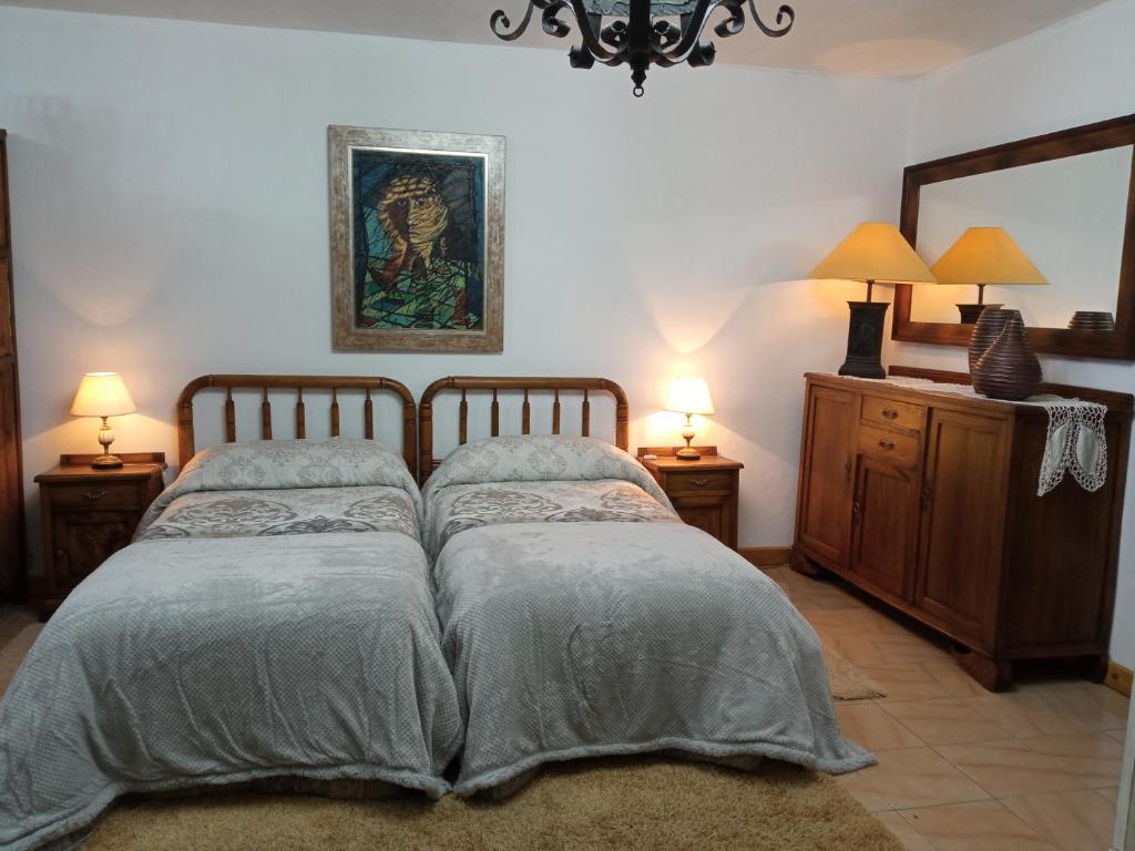 奥伦塞Casa MiraXurés con vistas a la Sierra del Xurés的一间卧室配有一张床、两盏灯和一面镜子