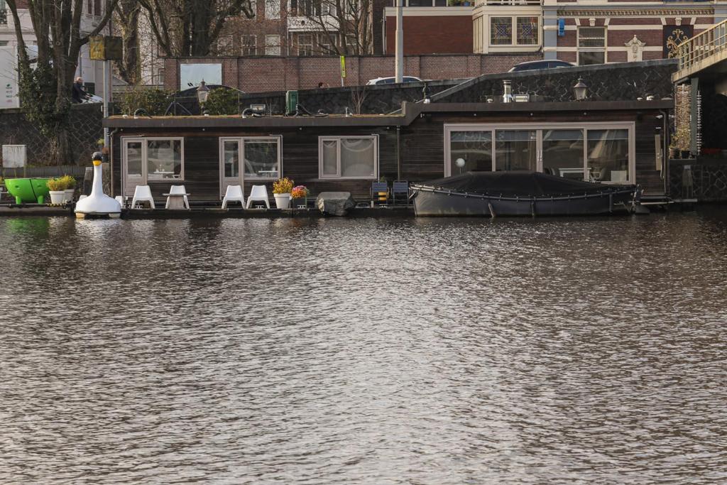 阿姆斯特丹小阿姆斯特尔船屋的水中带椅子和船的房子