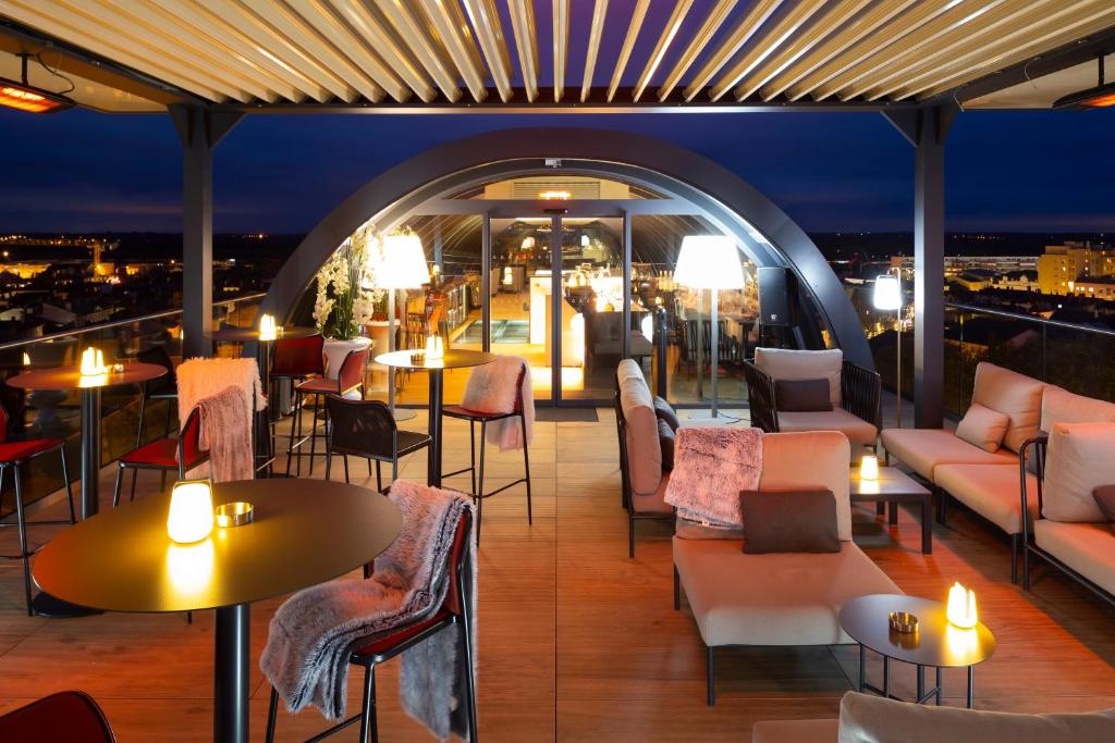 马孔HÔTEL & SPA Panorama 360的屋顶酒吧配有桌椅和灯光