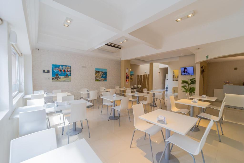 马德普拉塔Hotel Acqua的一间设有白色桌子和白色椅子的餐厅