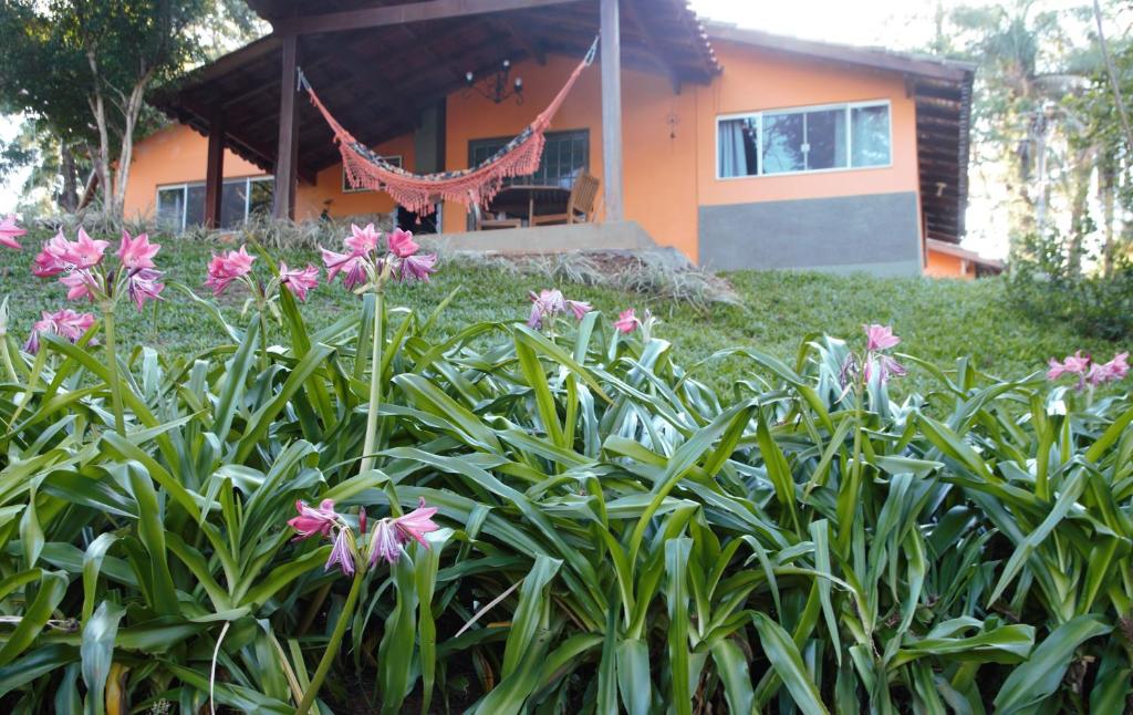 阿拉沙Chalé Bosque Do Barreiro的一座花园,在房子前方种有粉红色的花朵