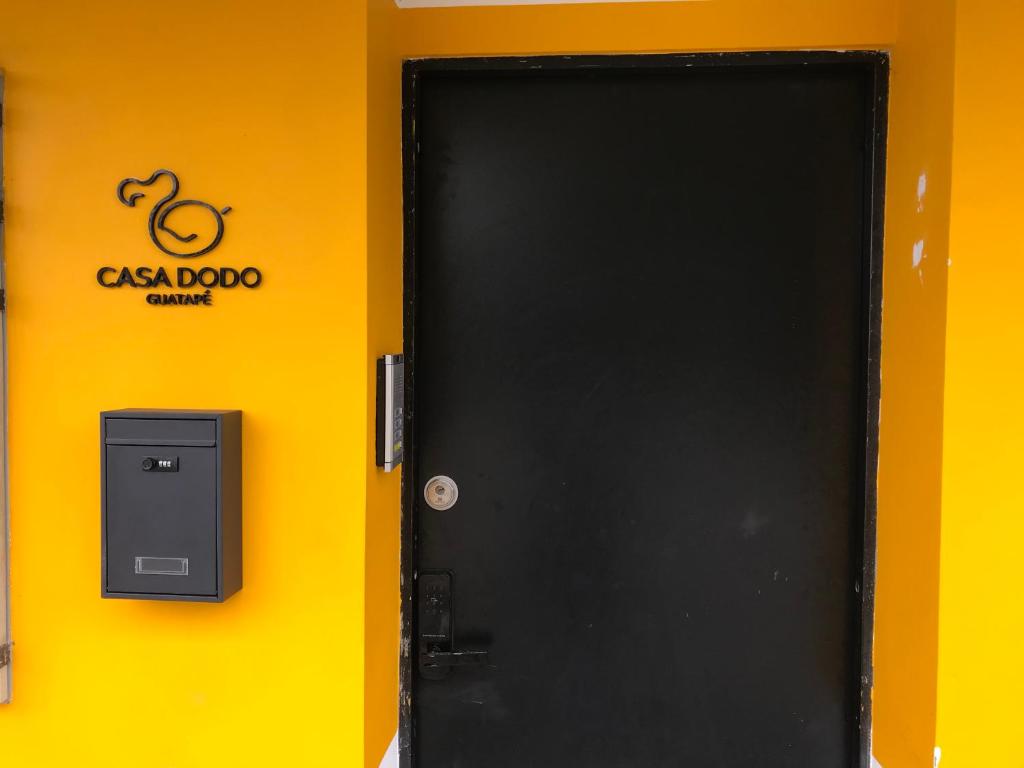 瓜塔佩Casa Dodo Guatapé的黄色墙上有标志的黑色门