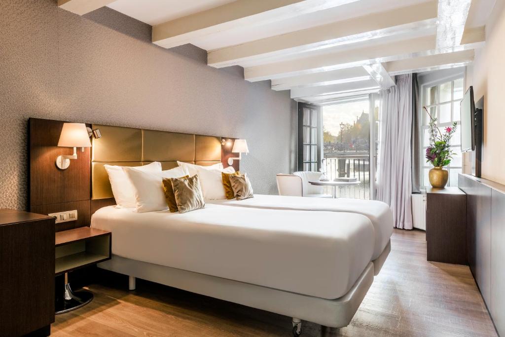 阿姆斯特丹NH精选巴比松皇宫公寓的酒店客房设有一张大床和一个阳台。