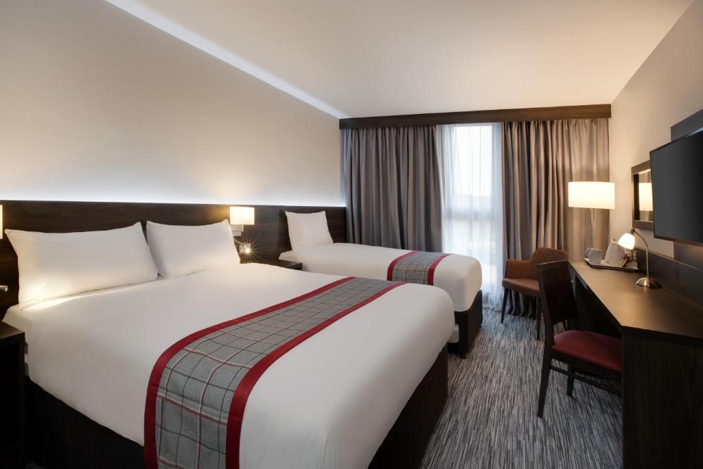 利兹Ramada by Wyndham Leeds East的酒店客房配有两张床和一张书桌