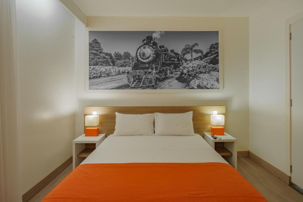 本图贡萨尔维斯Slim Bento Gonçalves的一间卧室配有一张带橙色毯子的大床