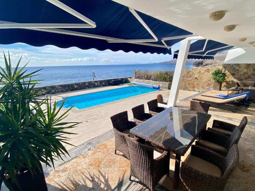 卡列罗港Seafront Puerto Calero Villa的一个带桌椅的庭院和一个游泳池