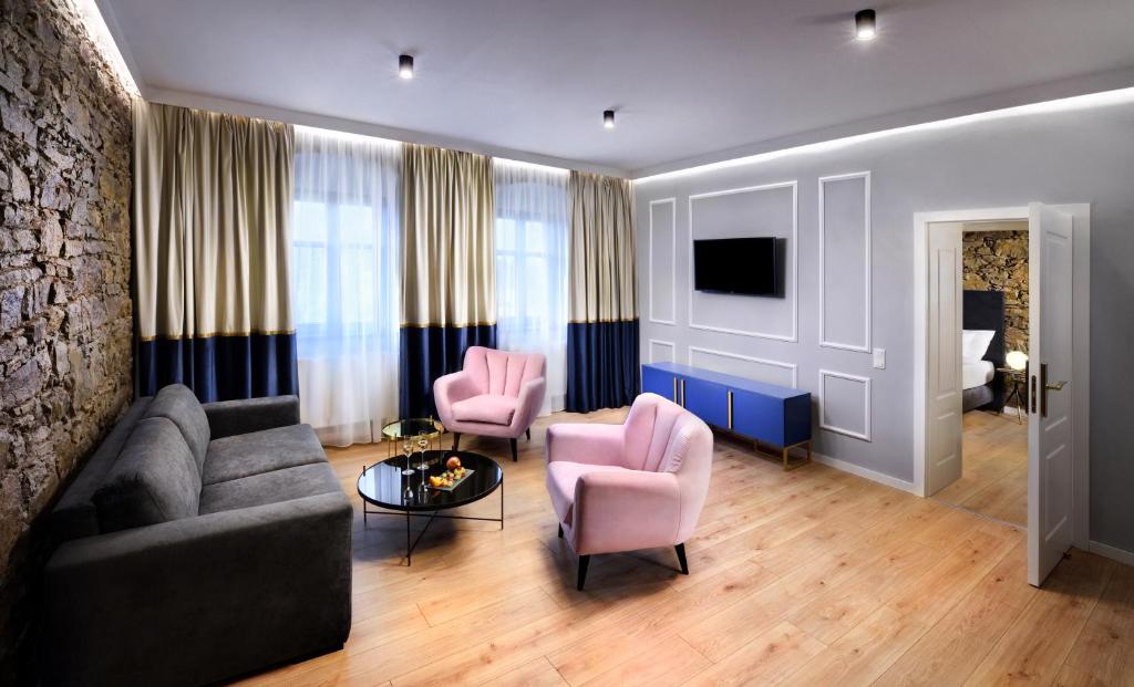 波普拉德Kalix Boutique Hotel的客厅配有沙发和2把粉红色的椅子