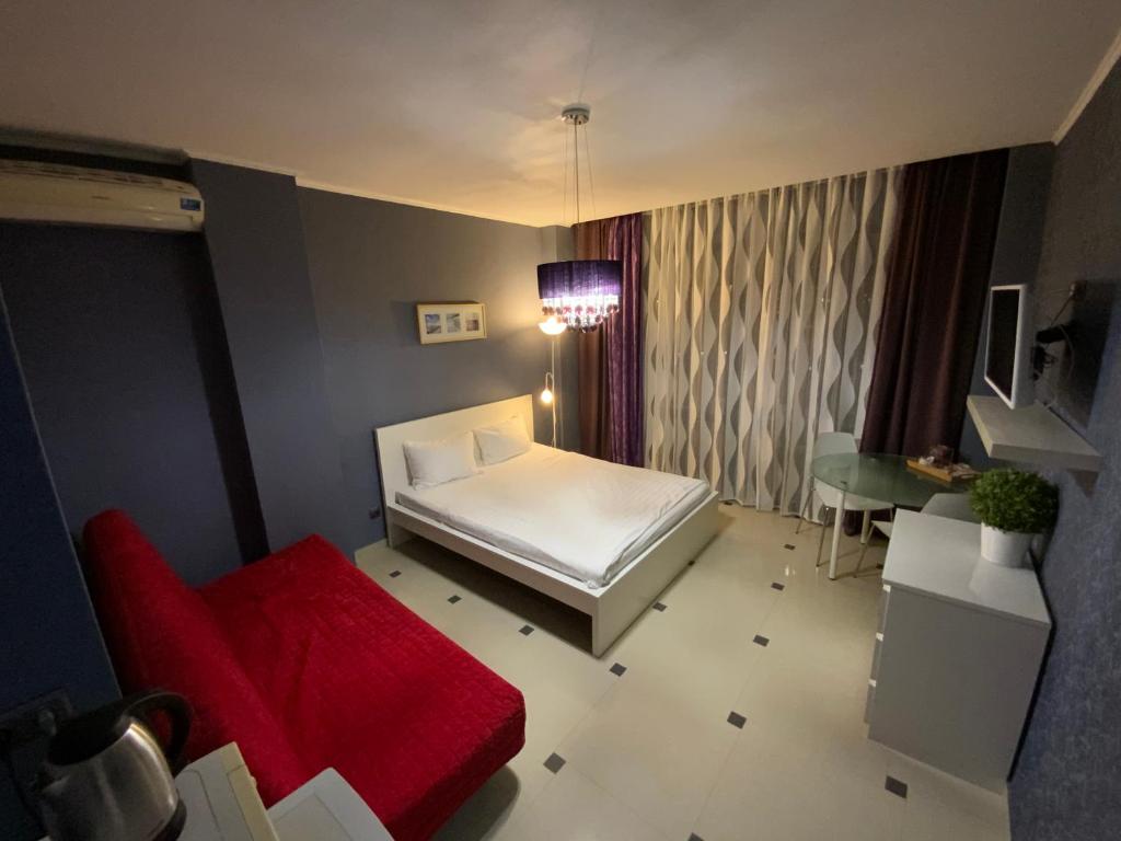 阿德勒阿莫索夫宾馆的卧室配有白色的床和红色沙发
