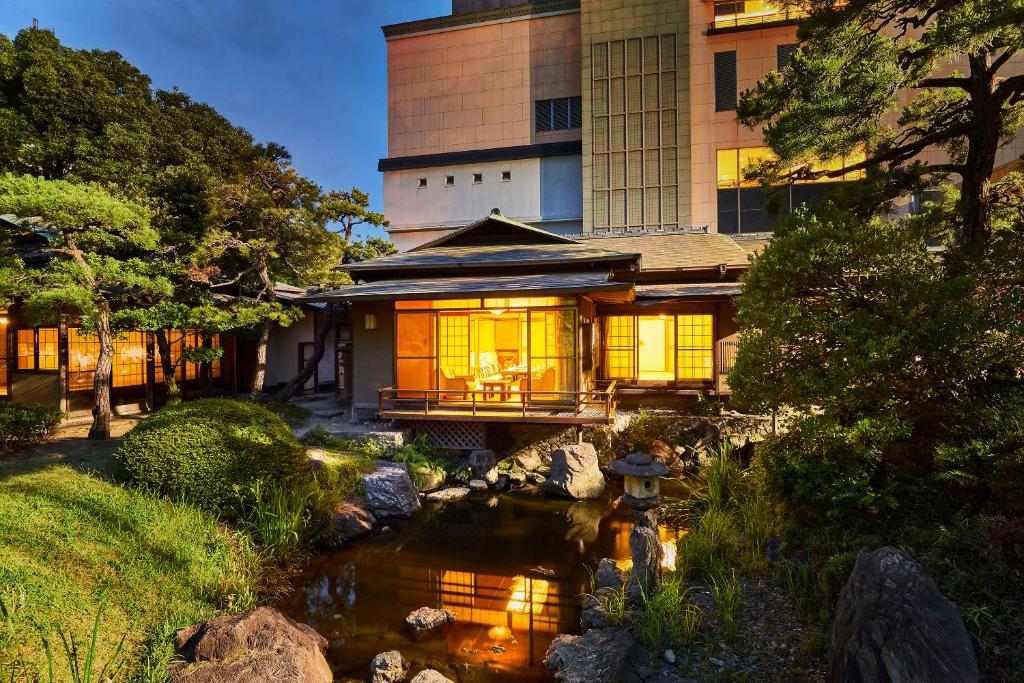 北九州Suisui Garden Ryokan (in the Art Hotel Kokura New Tagawa)的楼前有池塘的房子