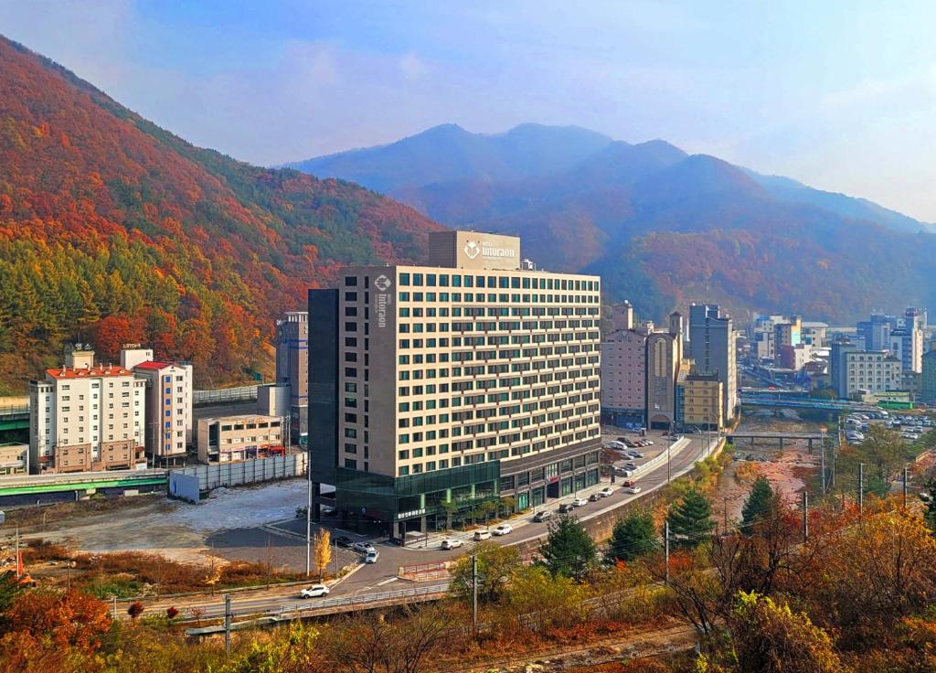 旌善Jeongseon Intoraon Hotel的一座大建筑,位于一个山丘背景的城市