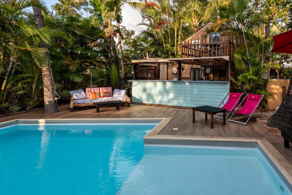 圣吉尔莱班Hôtel Coco Island的一个带两把椅子的游泳池以及一座房子