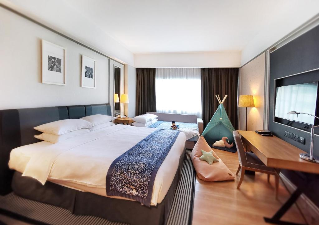 新加坡Orchard Hotel Singapore的一间卧室配有一张大床、一张书桌和电视。