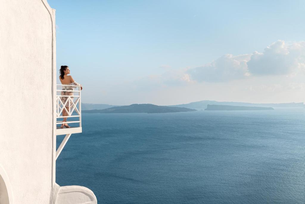 伊亚卡尔德拉尊贵别墅酒店的坐在一个俯瞰大海的阳台上的女人