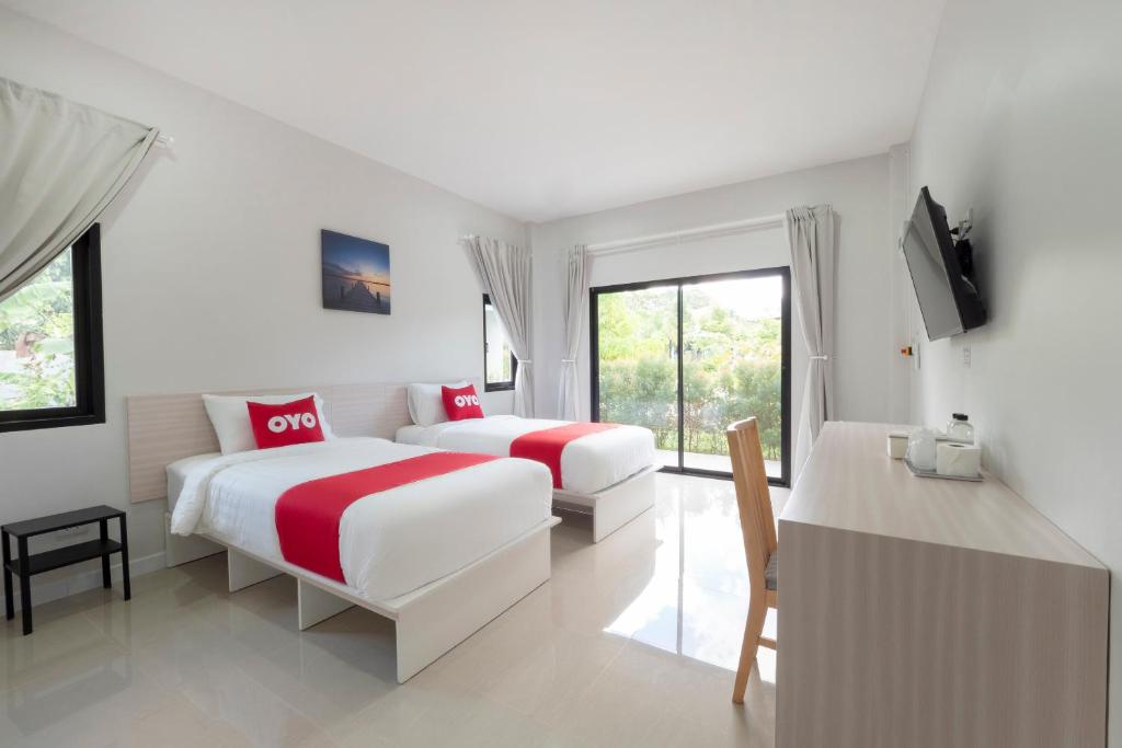 罗勇Capital O 75378 Thawapee Resort的一间卧室配有两张床、一台电视和一张桌子