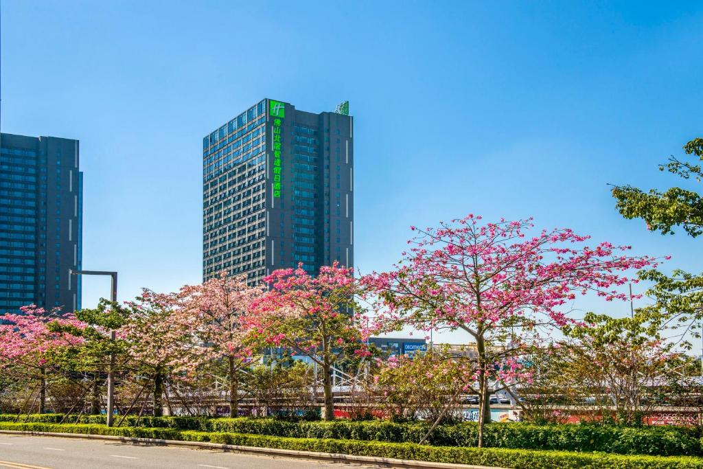 Shunde佛山北滘智选假日酒店的一座高楼前有樱树的城市