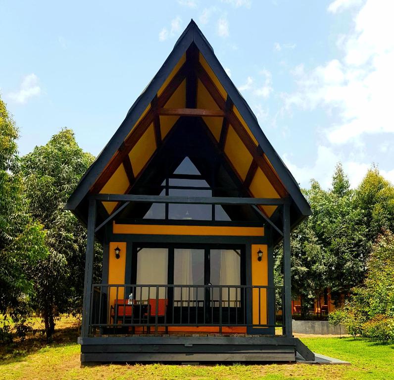 阿鲁沙Shamba lodge cabins的一间黑色和黄色屋顶的小房子