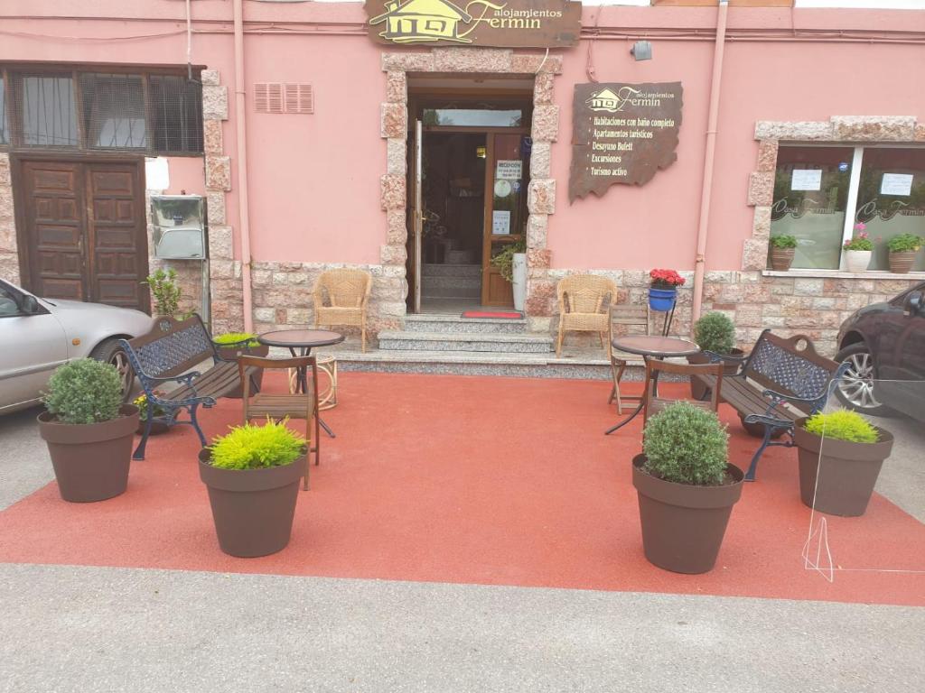 坎加斯-德奥尼斯费尔明住宿旅馆的一组桌子和椅子,位于一座粉红色的建筑前