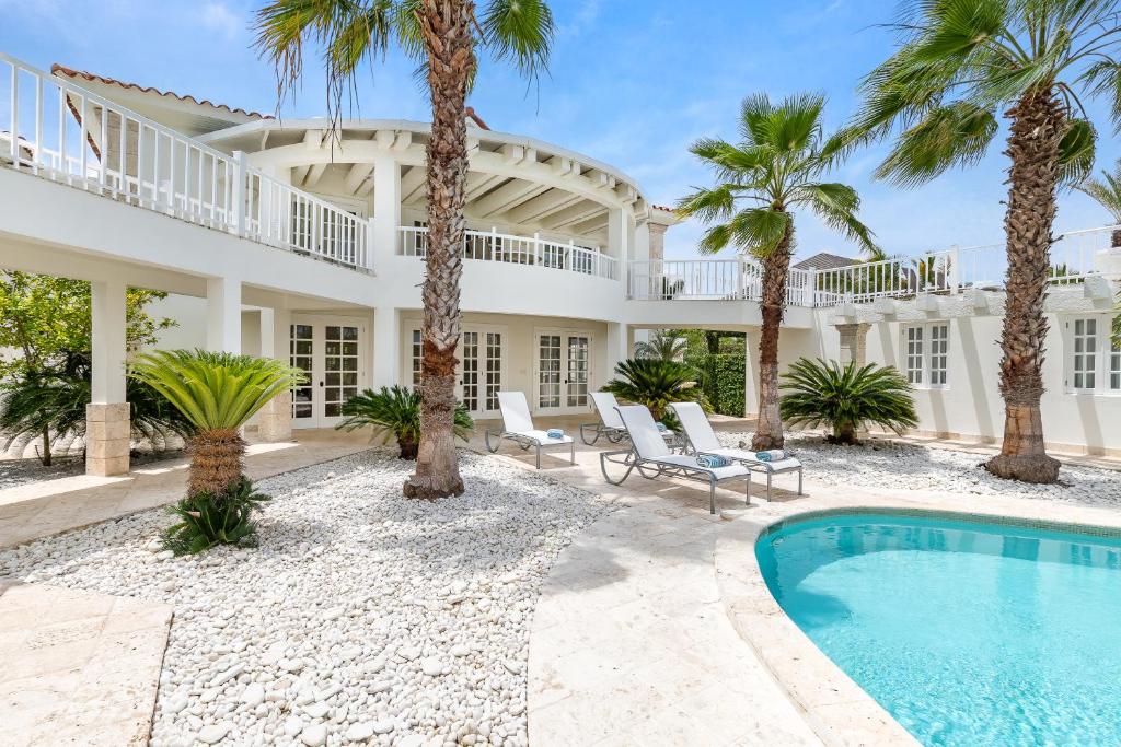 蓬塔卡纳Paradise Luxury Villa with Huge Pool and Jacuzzi的一座种植了棕榈树和游泳池的大型白色房屋