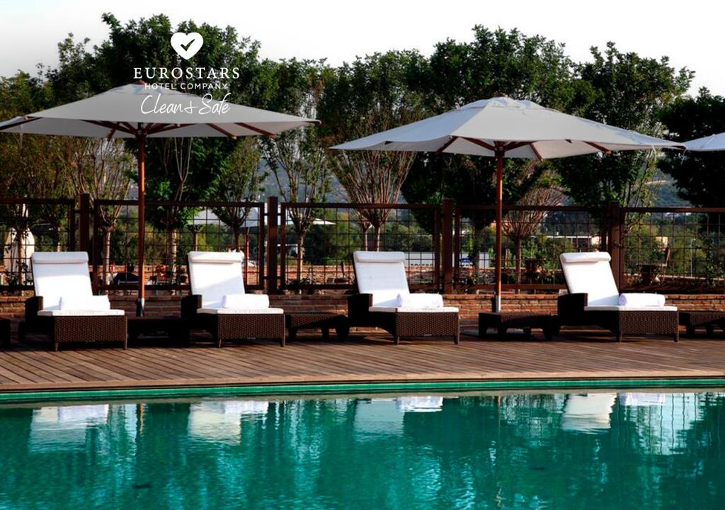 托莱多欧洲之星布埃纳维斯塔宫酒店的一组椅子和遮阳伞,位于游泳池旁