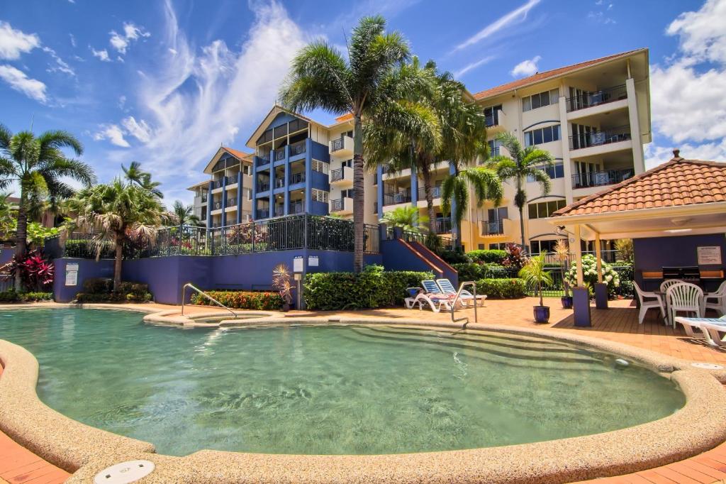 凯恩斯北湾海滨套房式酒店的棕榈树建筑前的游泳池