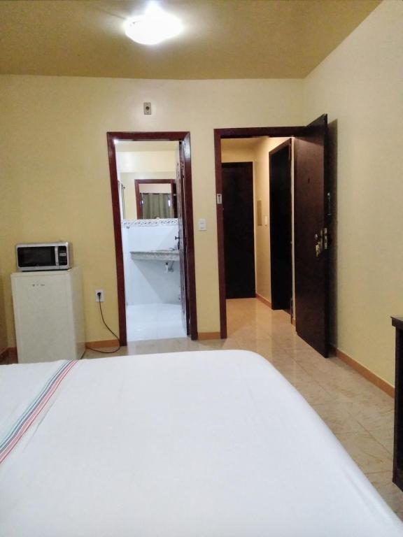 马瑙斯Hotel Saint Paul 02 Flat的一间卧室配有一张床,另一间则配有微波炉。