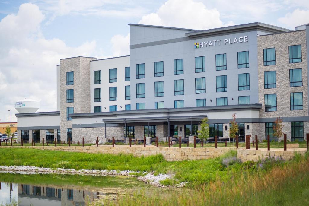 阿尔图纳Hyatt Place Altoona/Des Moines的前面有一条河流的建筑