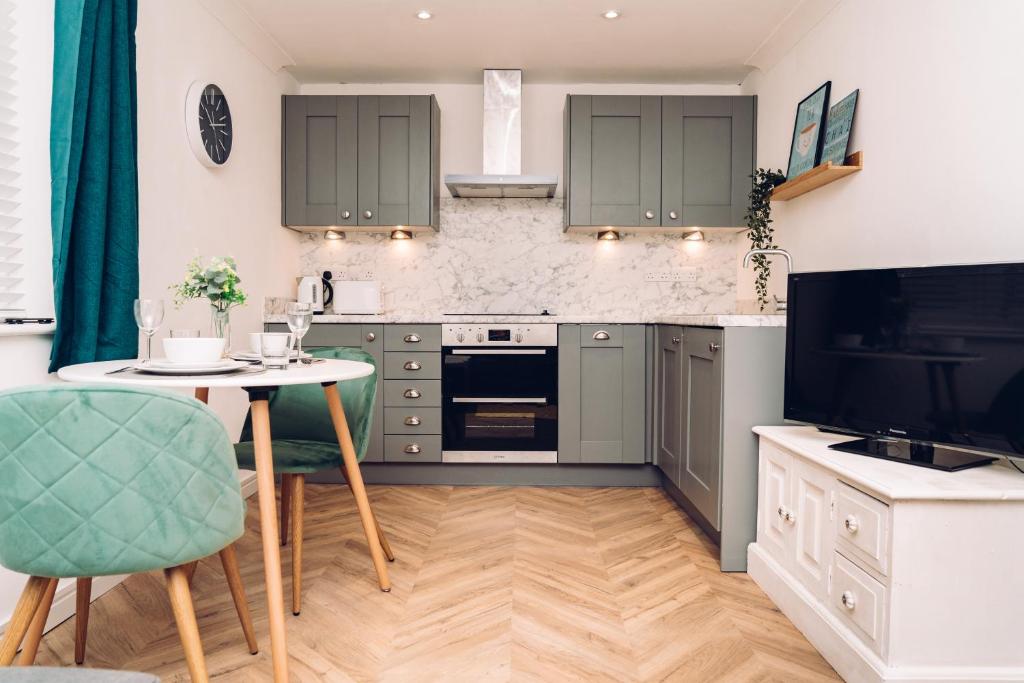 科尔切斯特Caroline Court - 1 Bedroom Apartment的厨房配有绿色橱柜、桌子和电视。