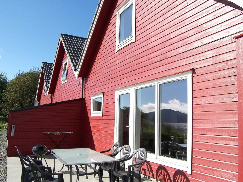 SørbøFour-Bedroom Holiday home in Sørbøvåg 1的一座红色的建筑,前面设有桌椅