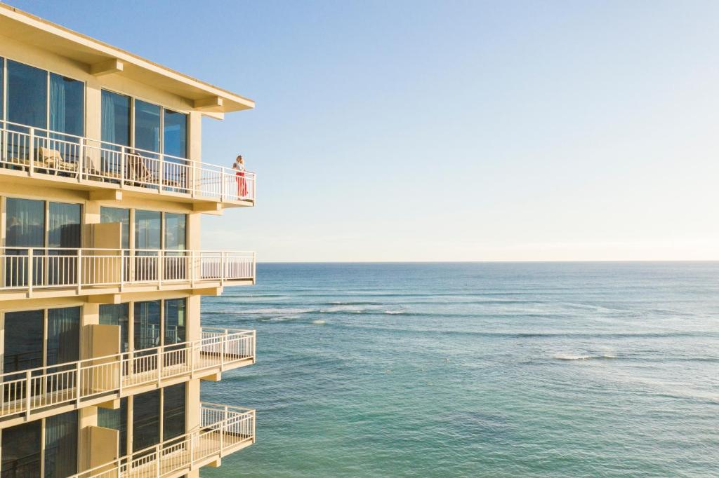 檀香山Kaimana Beach Hotel的一座俯瞰大海的建筑,阳台上有人