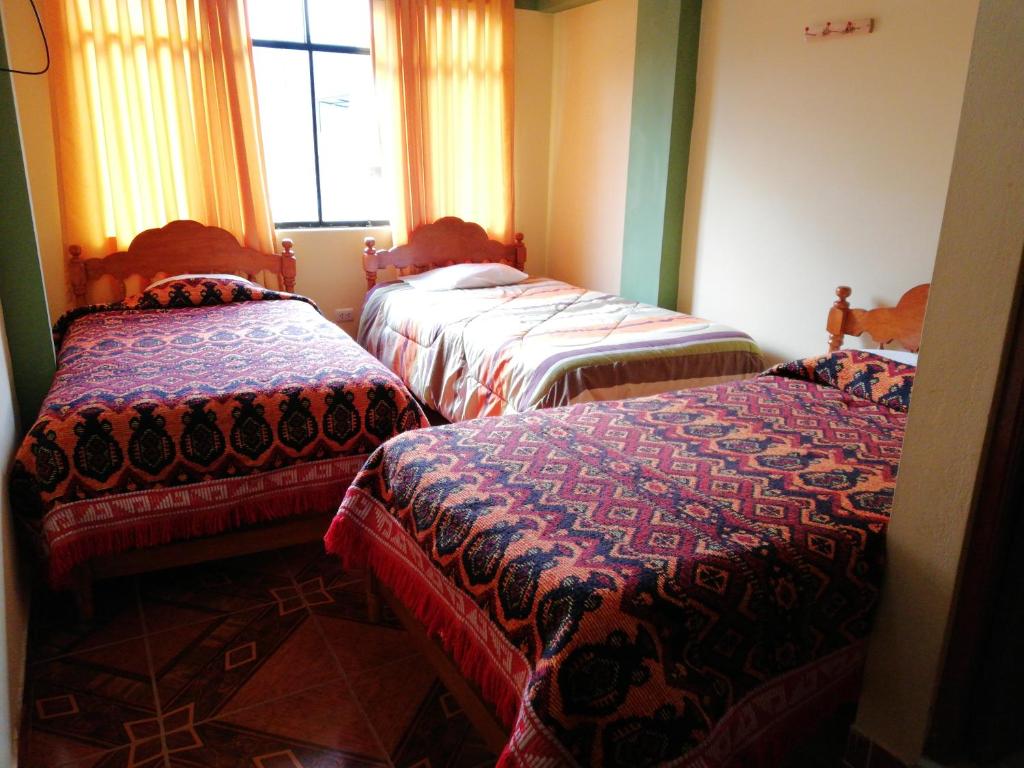 瓦拉斯Artesonraju Hostel Huaraz的带窗户的客房内的三张床