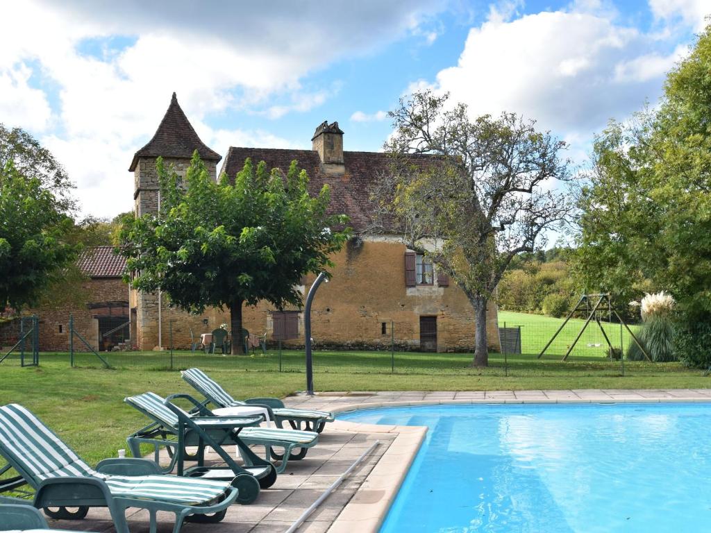 Saint-PompontVintage Holiday Home in Besse with Swimming Pool的一个带椅子的游泳池和一个背景房子