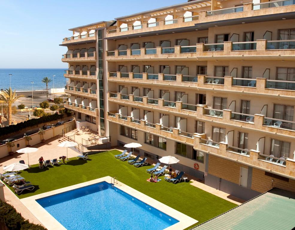 托雷德尔马尔BQ安达卢西亚海滩酒店的背景是一座带游泳池和大海的酒店