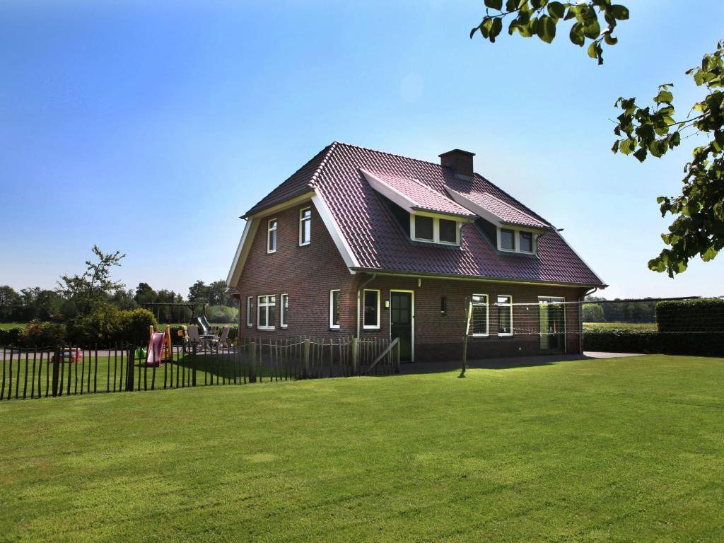 NeedeSpacious farmhouse in Achterhoek with play loft的绿色庭院中一座红色屋顶的房子