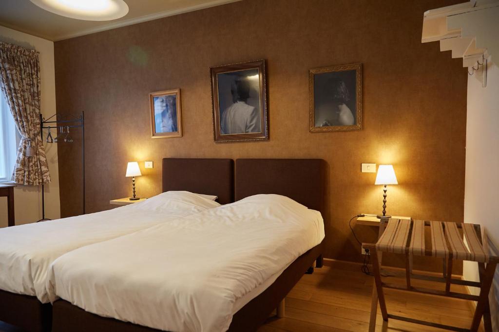 科特赖克Focus Hotel的卧室配有一张床和两张桌子,墙上有两张照片