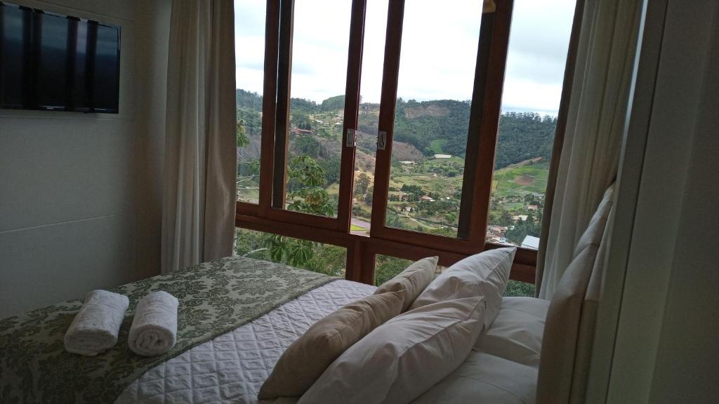 多明戈斯马丁斯Apart Hotel Vista Azul - hospedagem nas montanhas的卧室设有大窗户、一张床和枕头