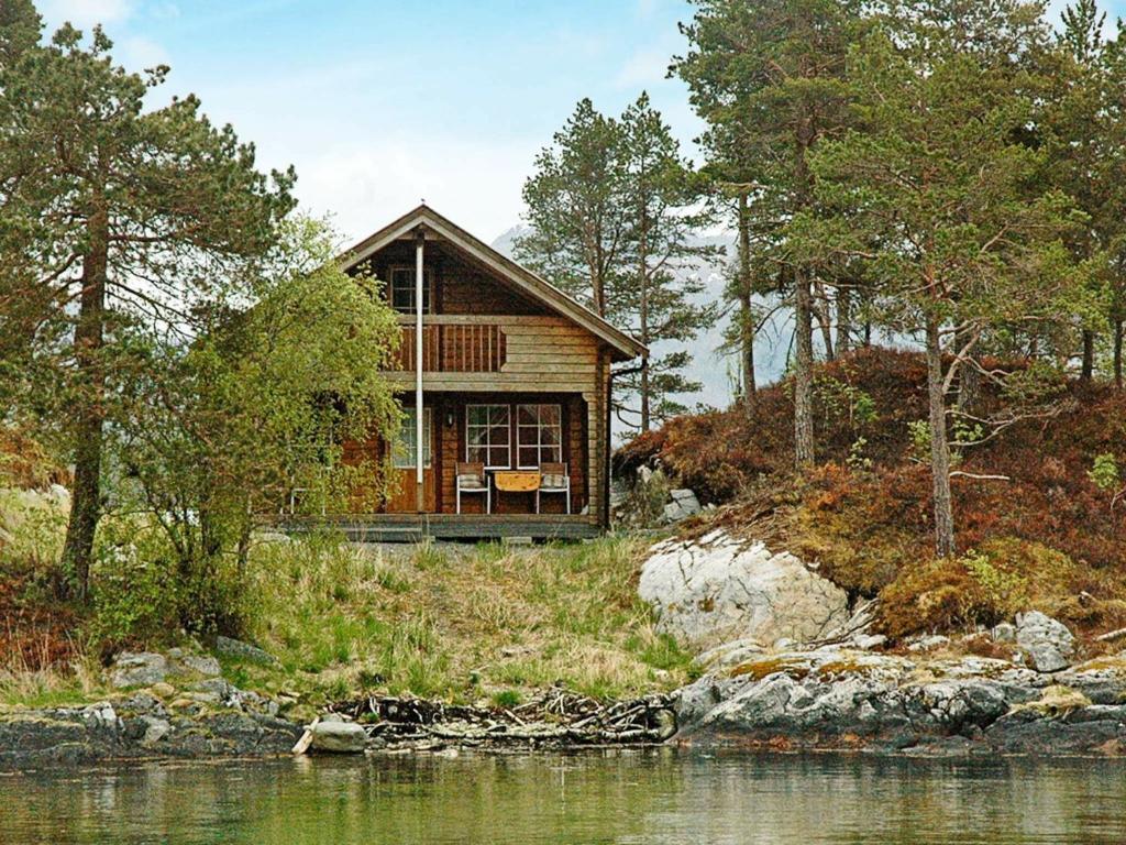 BårdsetTwo-Bedroom Holiday home in Vågland 6的水体旁山丘上的房屋
