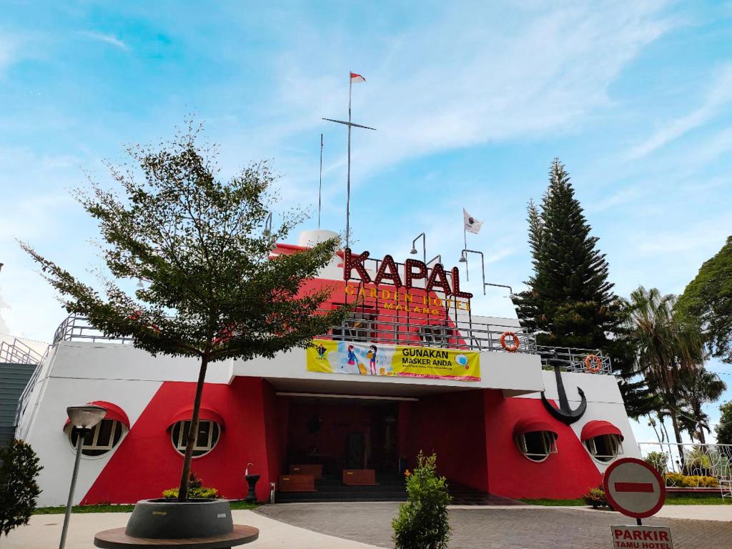 玛琅Kapal Garden Hotel Malang的一座红色和白色的建筑,上面有标志